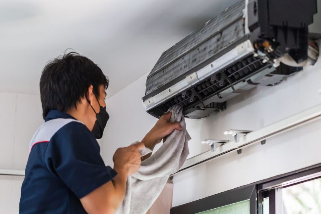 A technician using rug to clean the wall mounted aircon